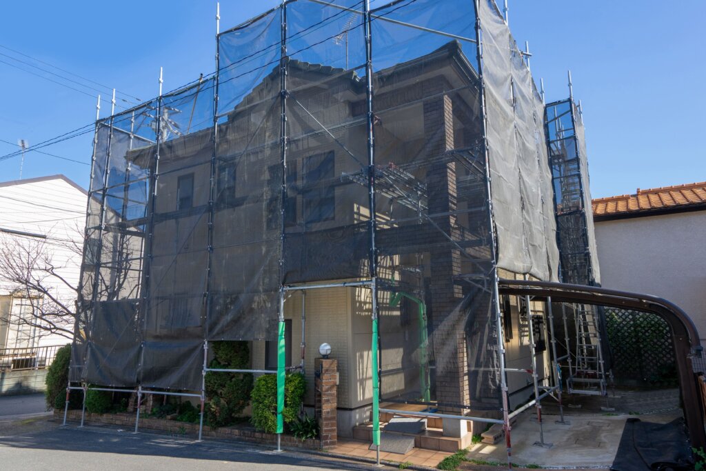 足場と養生シートに囲まれた住宅